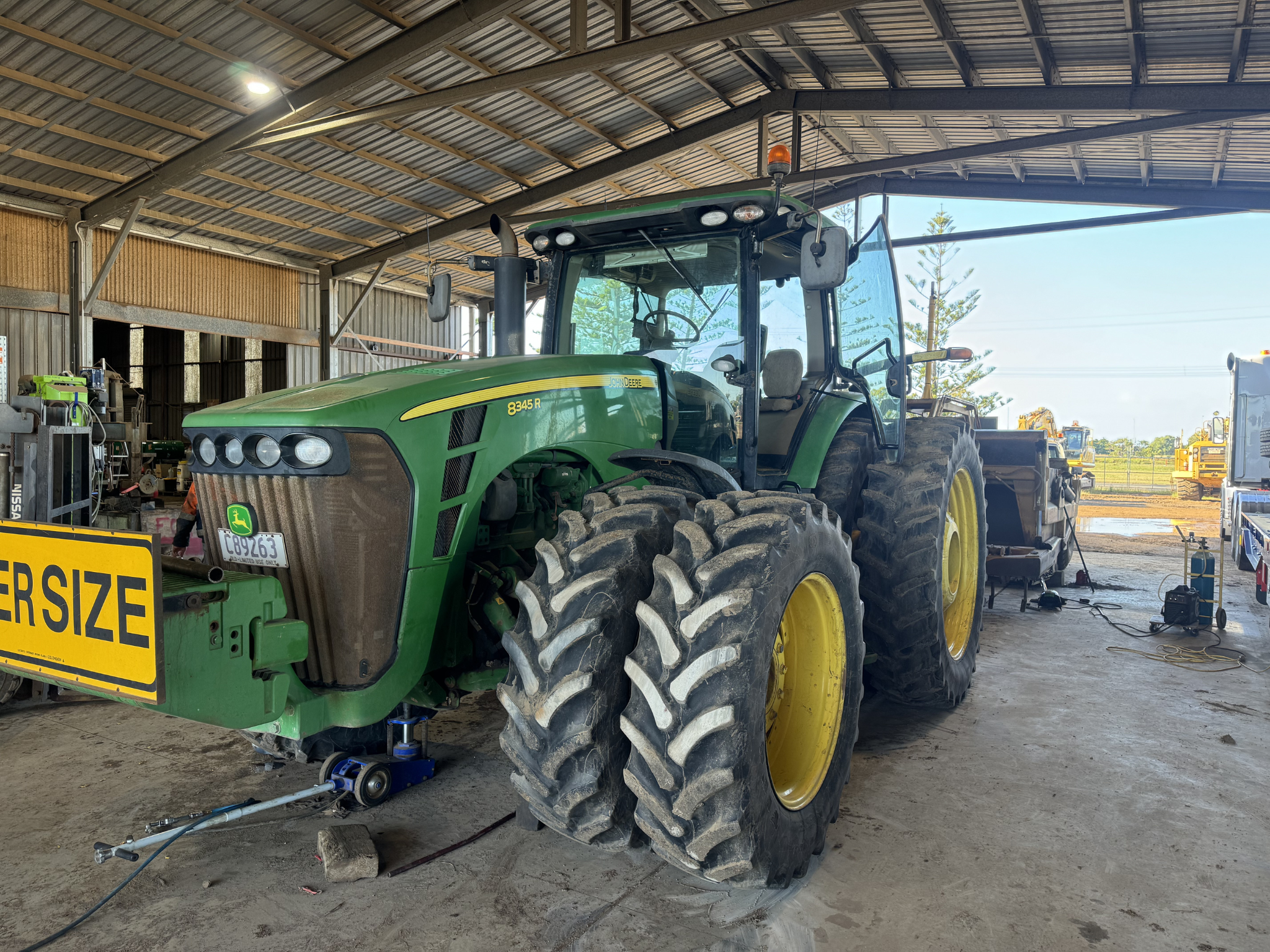 Large agricultural tractor undergoing inspection and repair in shed for diesel and machinery servicing