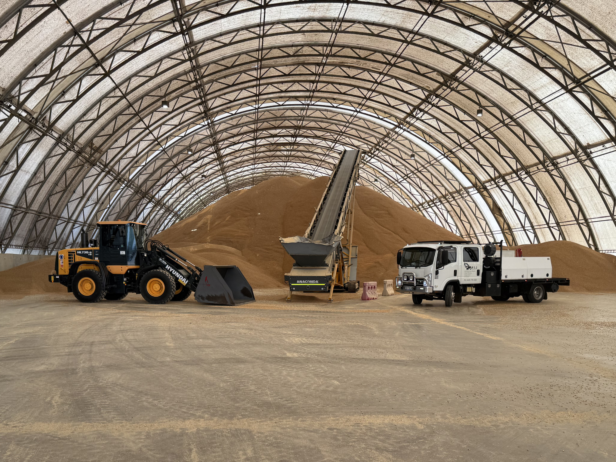 Loader and trucks inside bulk storage shed for earthmoving and material handling services by NLJ Contracts